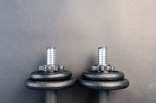 Close-up of two iron dumbbells on a gray background, perfect for strength training images.